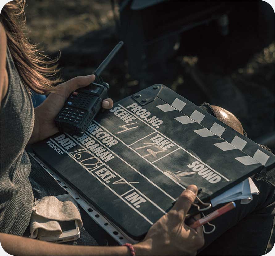A woman holding a movie clapperboard and a walkie talkie